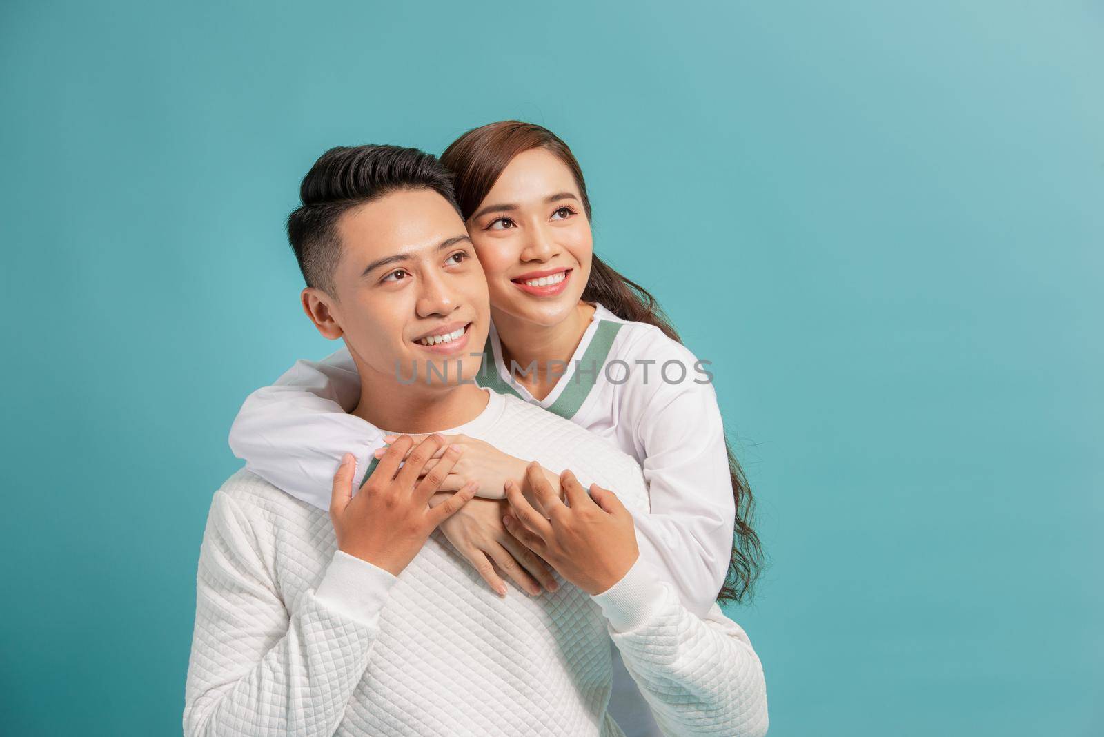 Studio shot of romantic couple posing with smile. Front view of girl and boy hugs on blue background.