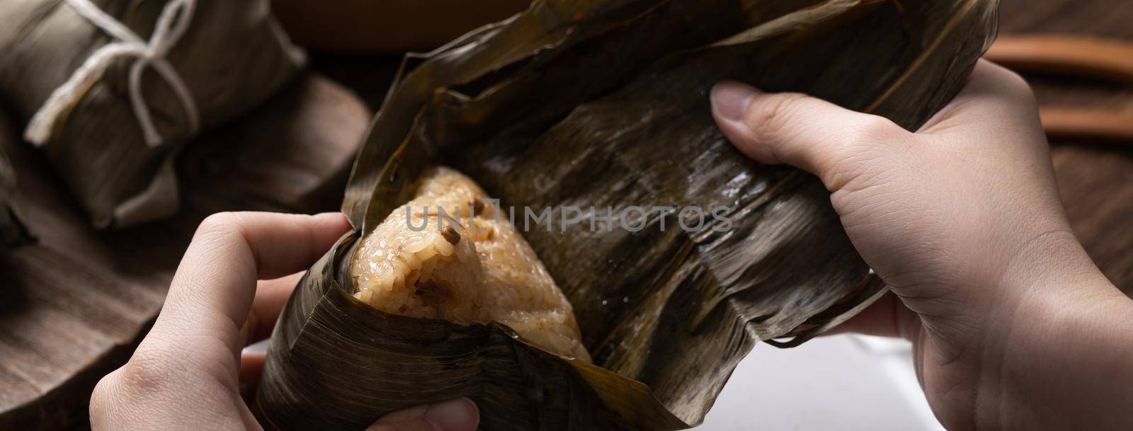 Eating Zongzi rice dumpling for Chinese traditional Dragon Boat Festival (Duanwu Festival) celebration event concept.
