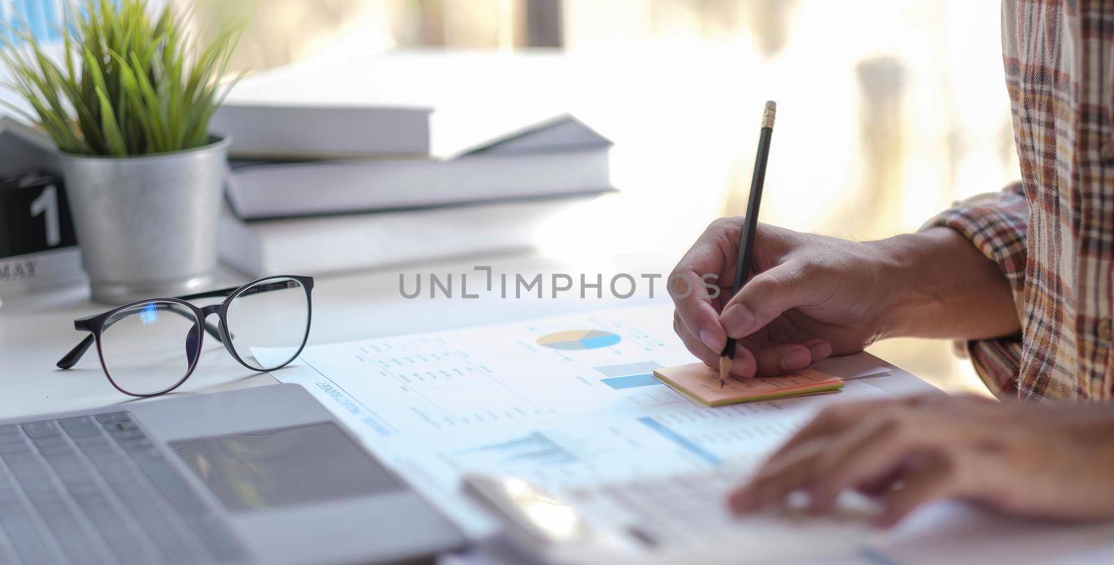 Hand man doing finances and calculate on desk about cost at home office. by wichayada