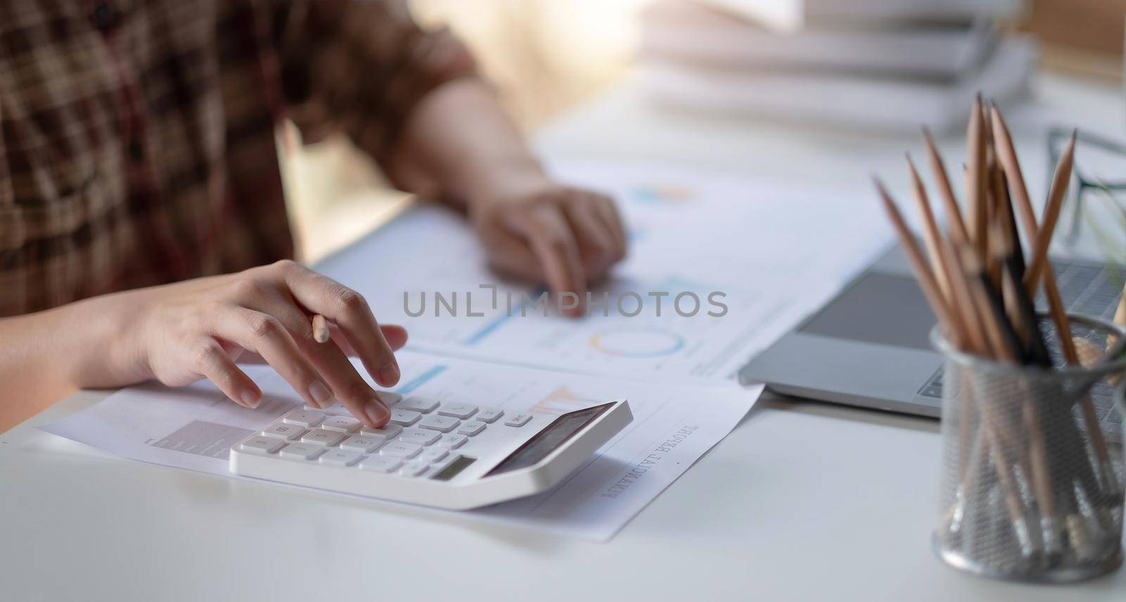 Businessman calculates financials with graph paper on the table on the cost of home office in the evening. by wichayada