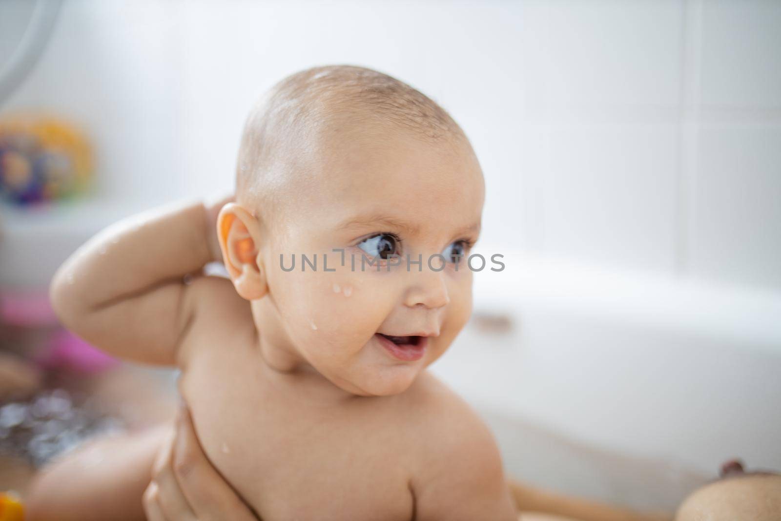 Happy and smiling baby in a white bathtub by Kanelbulle
