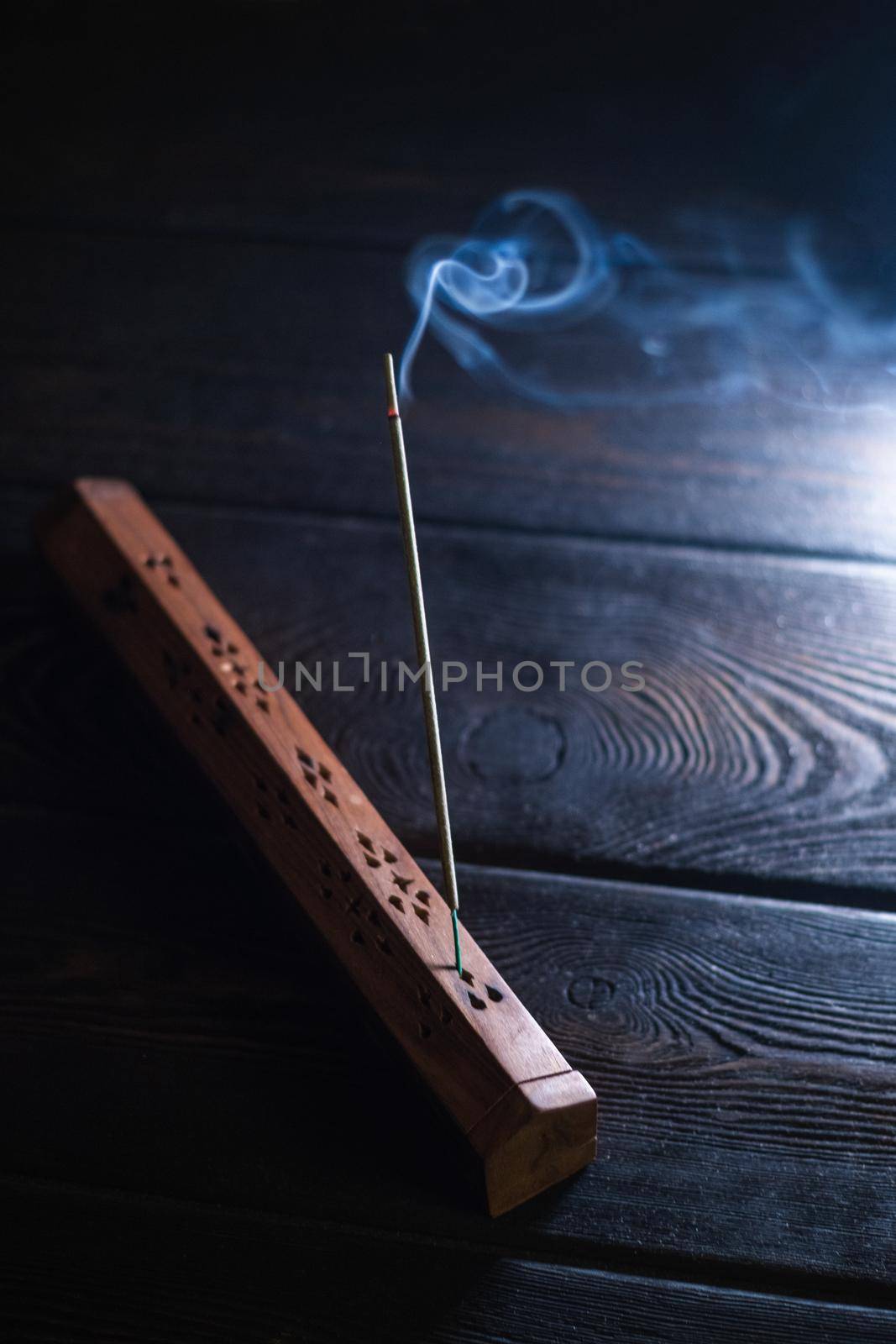 Focus on incense stick and smoke in a wooden stand. Symbol Japanese culture