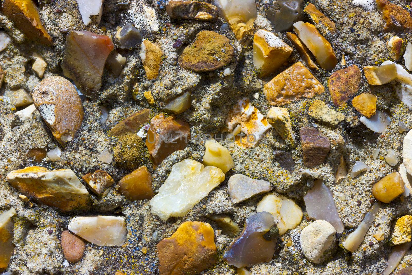 A rough pebble dash covering on an external wall showing small stones of various shapes and colours