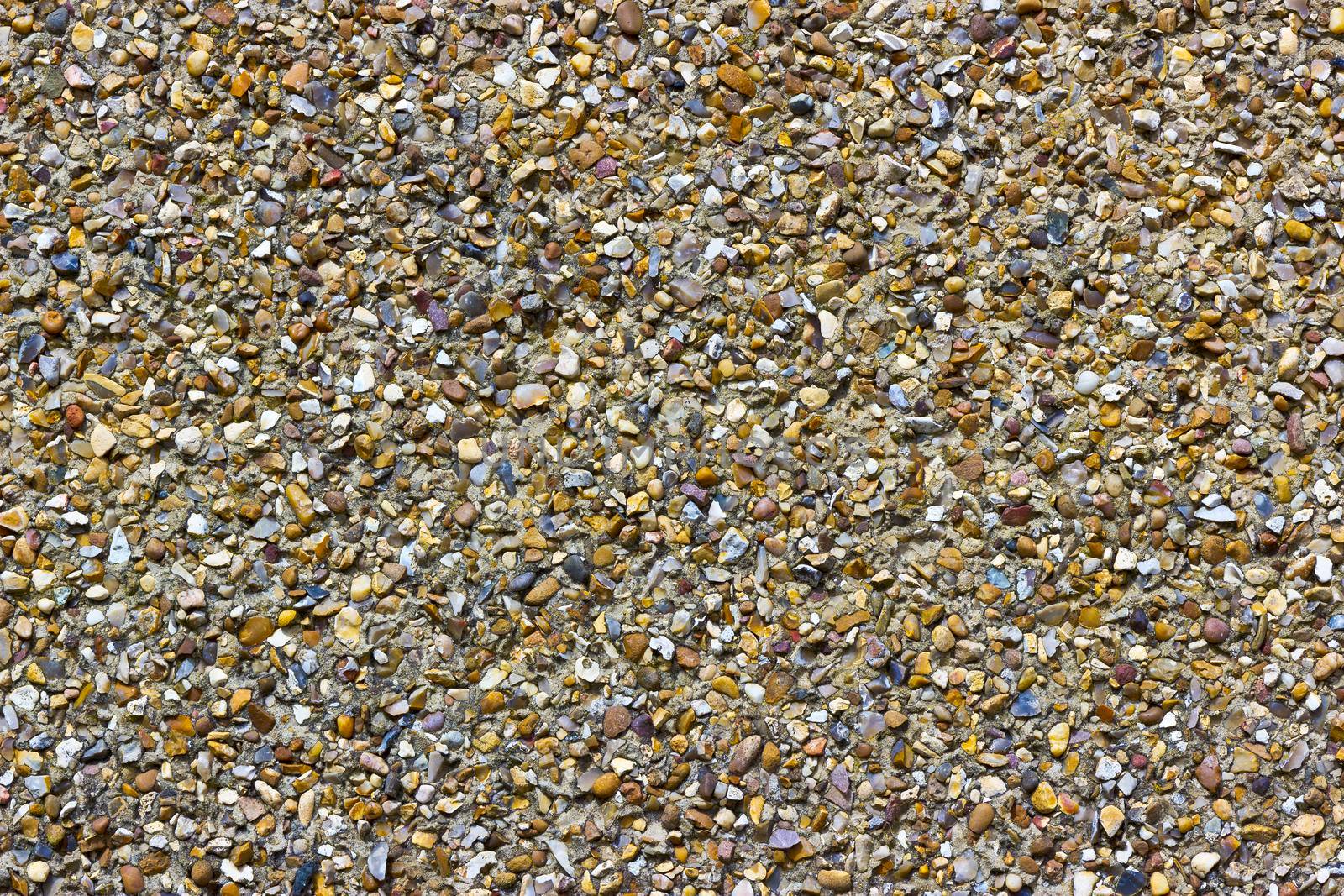 A rough pebble dash render on an external wall showing small stones of various shapes and colours