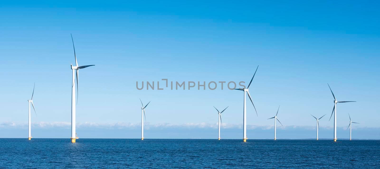 wind turbines in water of ijsselmeer near Urk in dutch part of noordoostpolder under blue sky in the netherlands