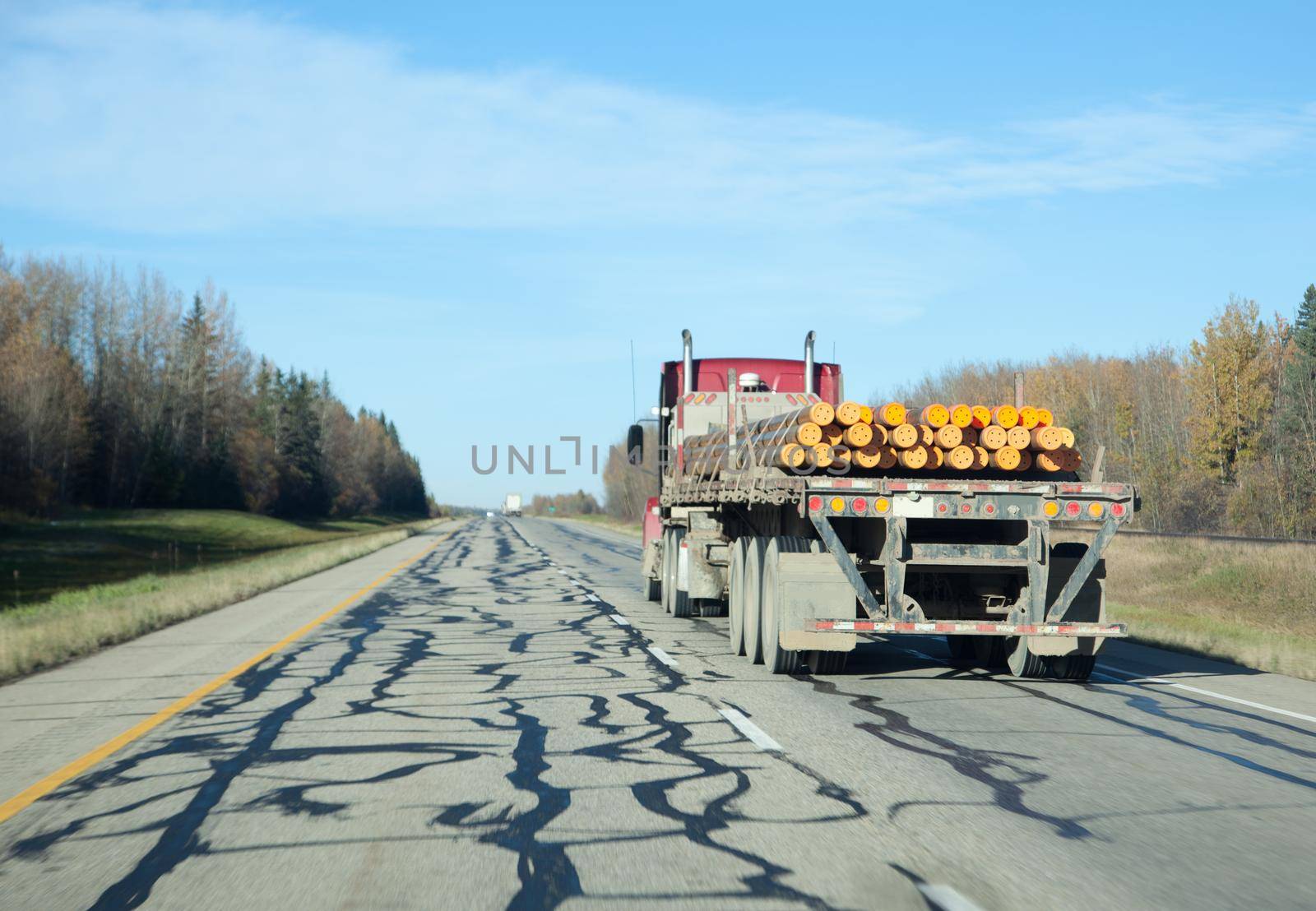 a transfer or 18 wheeler carrying pipes on a highway in blue sky 