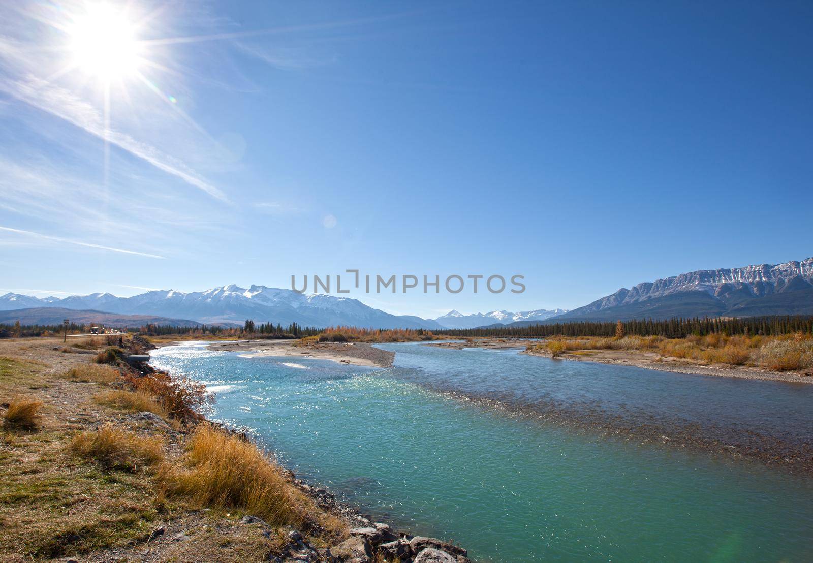 the turquoise Athabasca river with blue sky and sun flare in Jasper National Park, Alberta