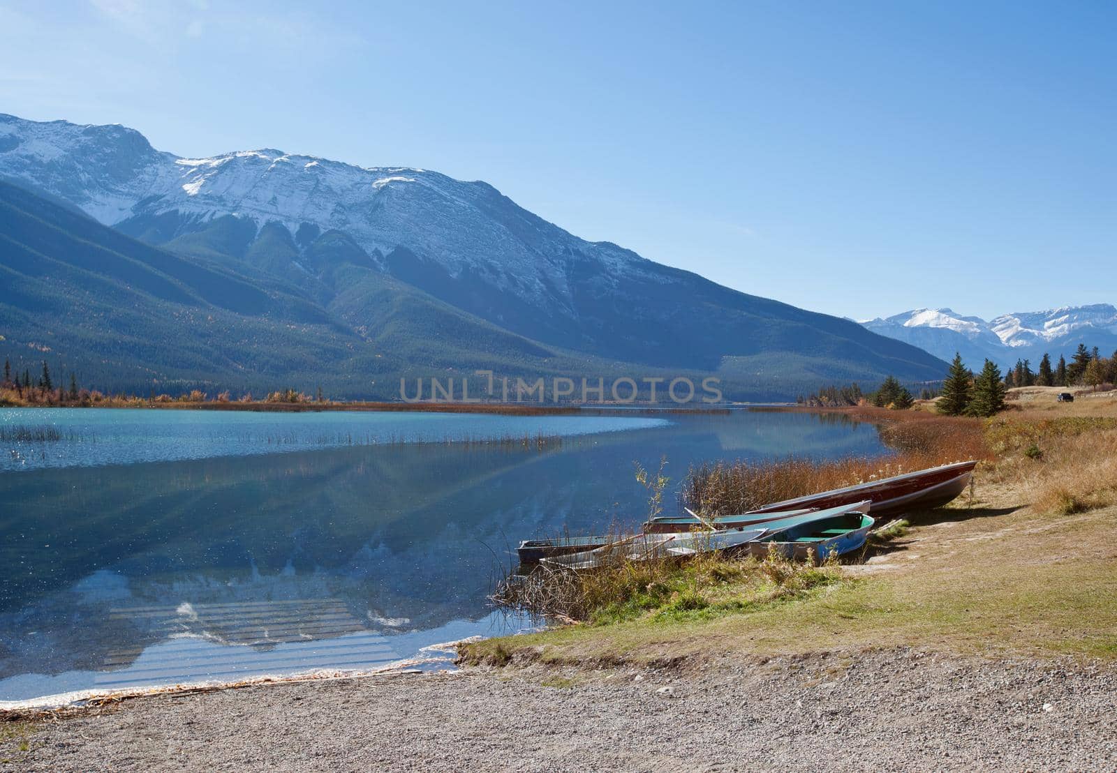 rowboats by the lakeside with gorgeous rocky mountain range behind in Canada