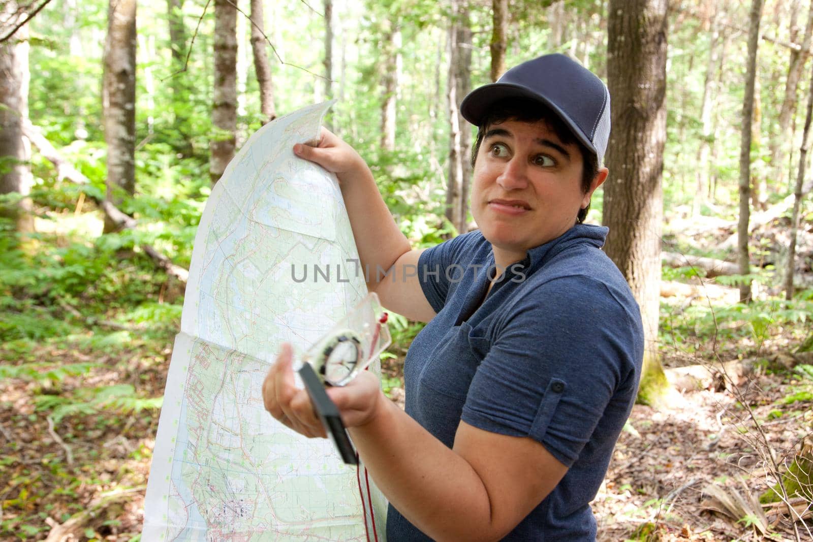 Person with a map and compass is lost in the woods, expression unsure where to go 