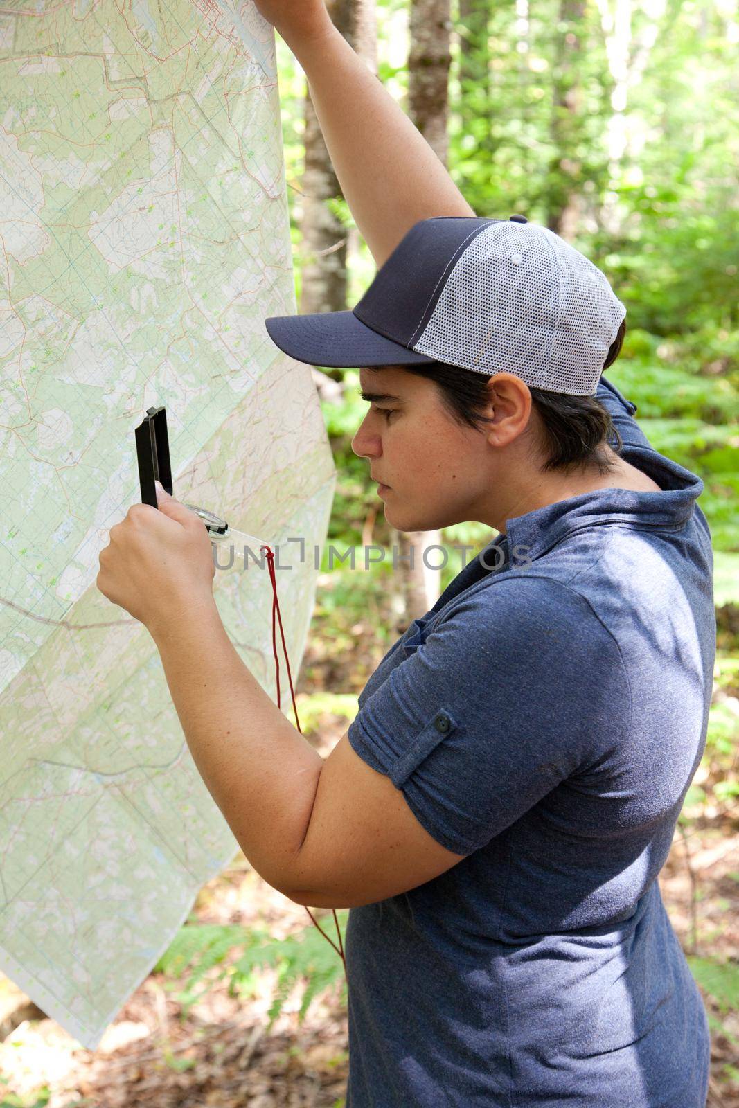Person in the woods uses a map and compass to find their way 