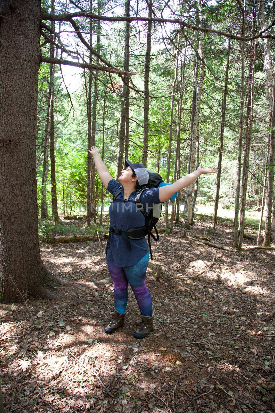 Person outside in the woods smiling with arms open feeling free and happy to be traveling