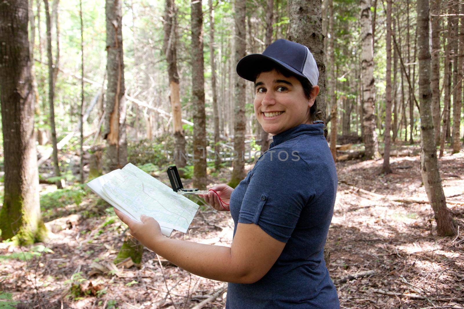Person smiling in the woods with the proper tools like compass and map 