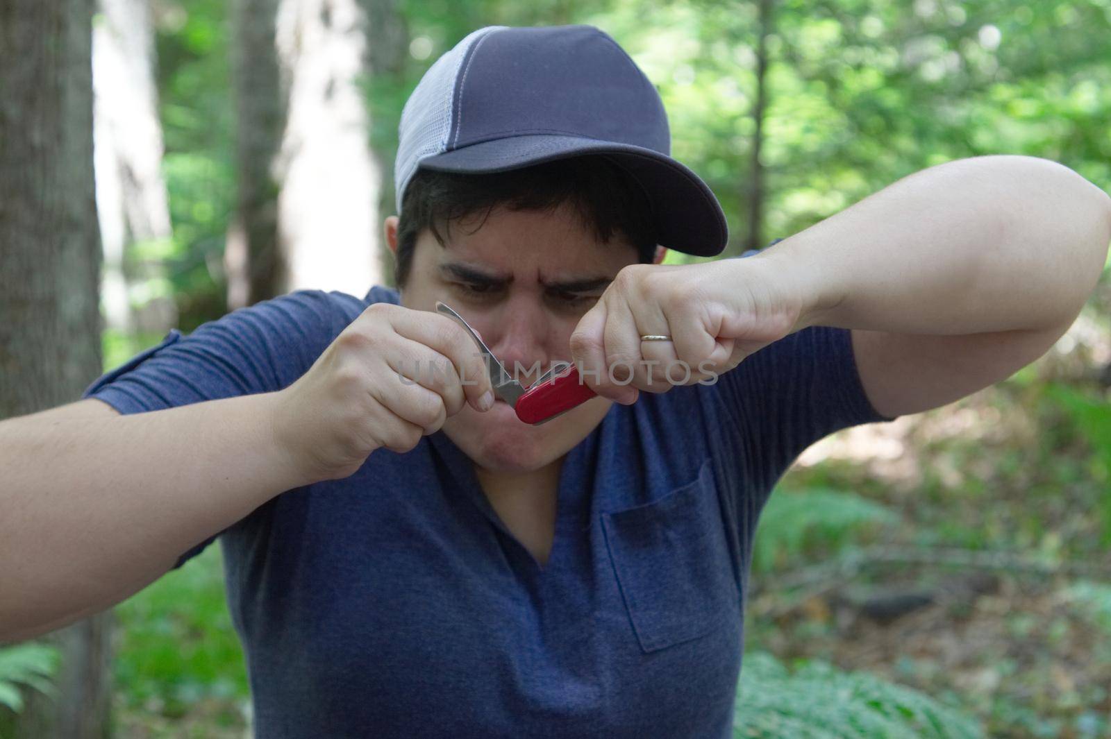 Woman looks confused as she tries to use a jack knife or utility tool in the woods