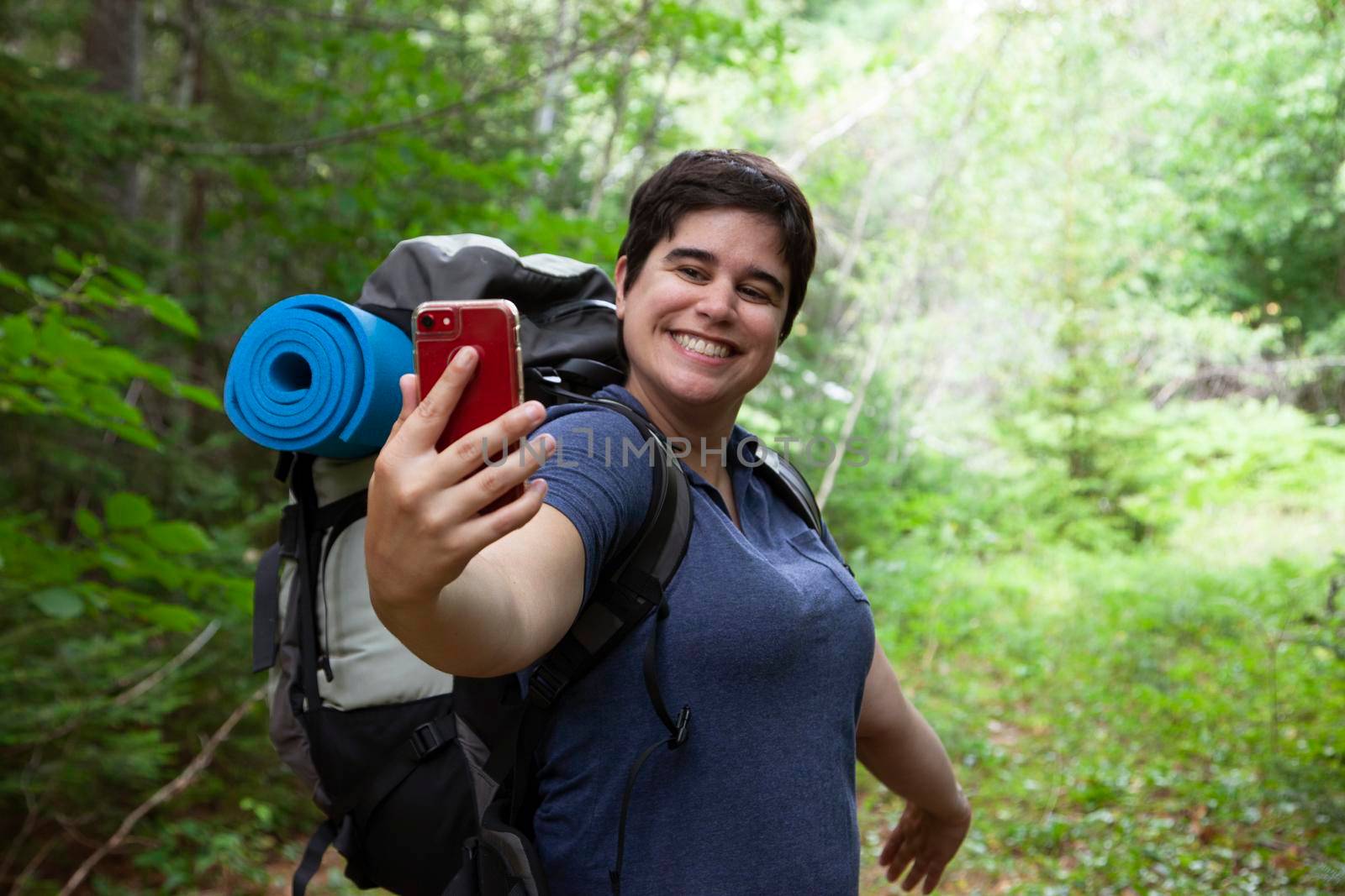 millennial grinning at their cell phone while exploring nature 