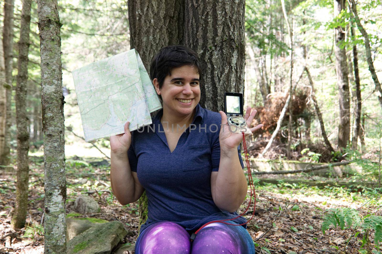 Woman in the forest smiles as she is prepared to navigate her way through the woods