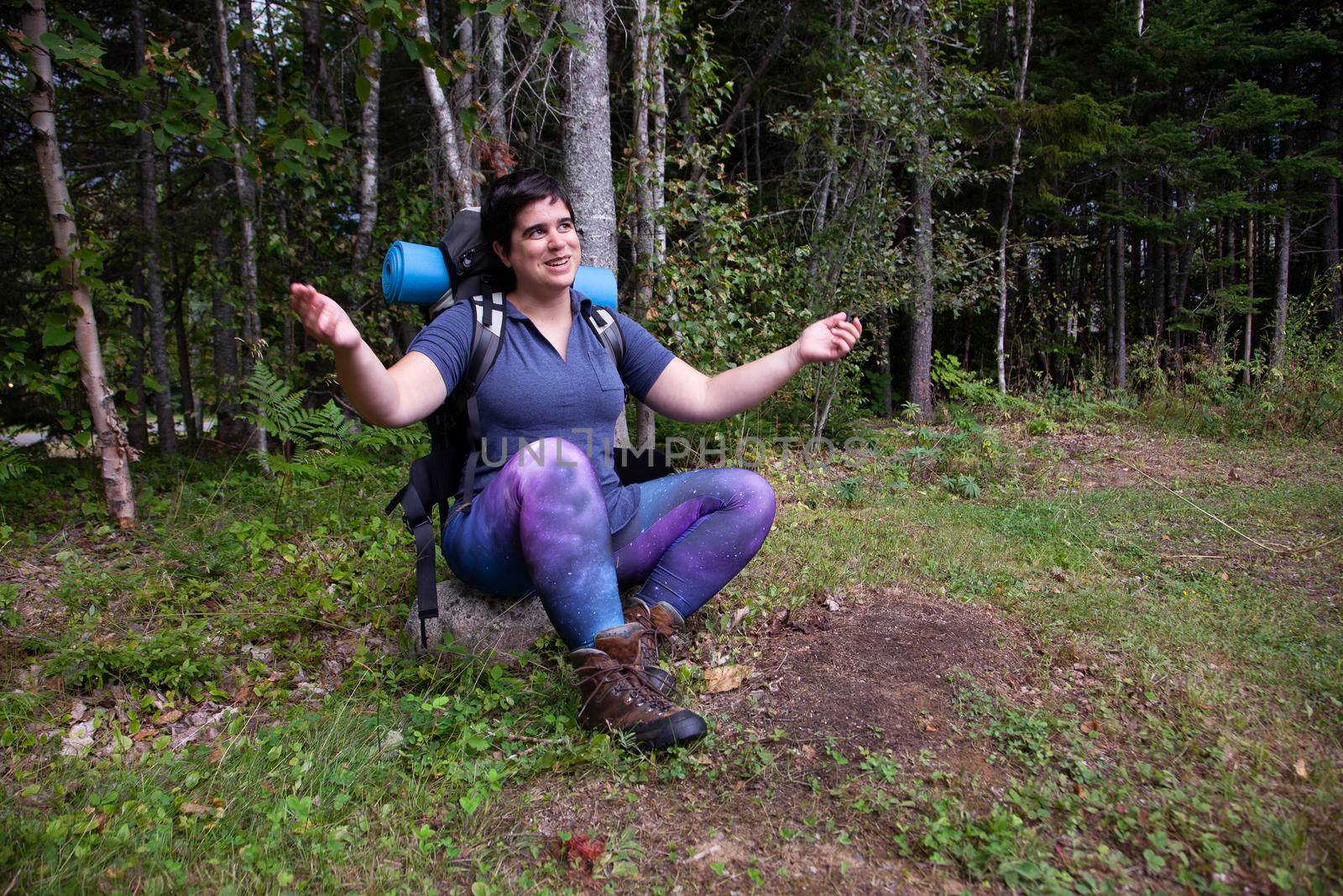 woman sitting on a rock with arms open, ready for a hike embracing the outdoors 