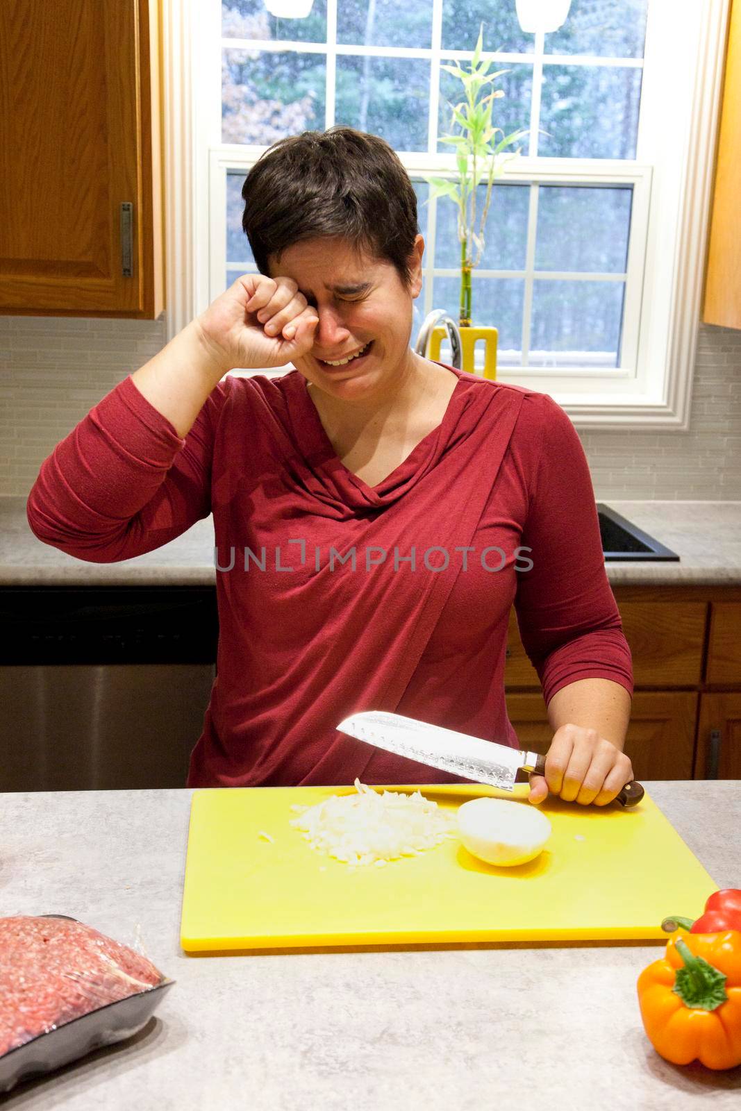 Woman bawling her eyes out while cutting an onion in the kitchen 