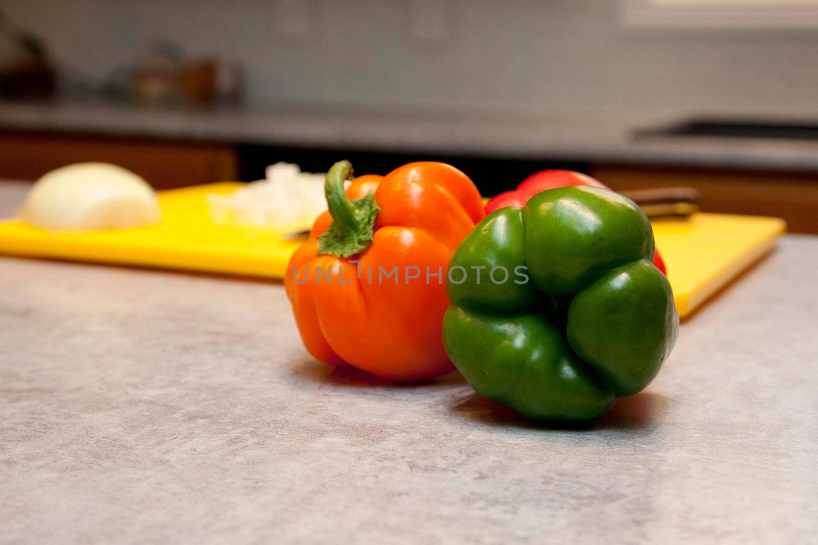  Red and green bell peppers next to a cutting board in the kitchen with copy space 