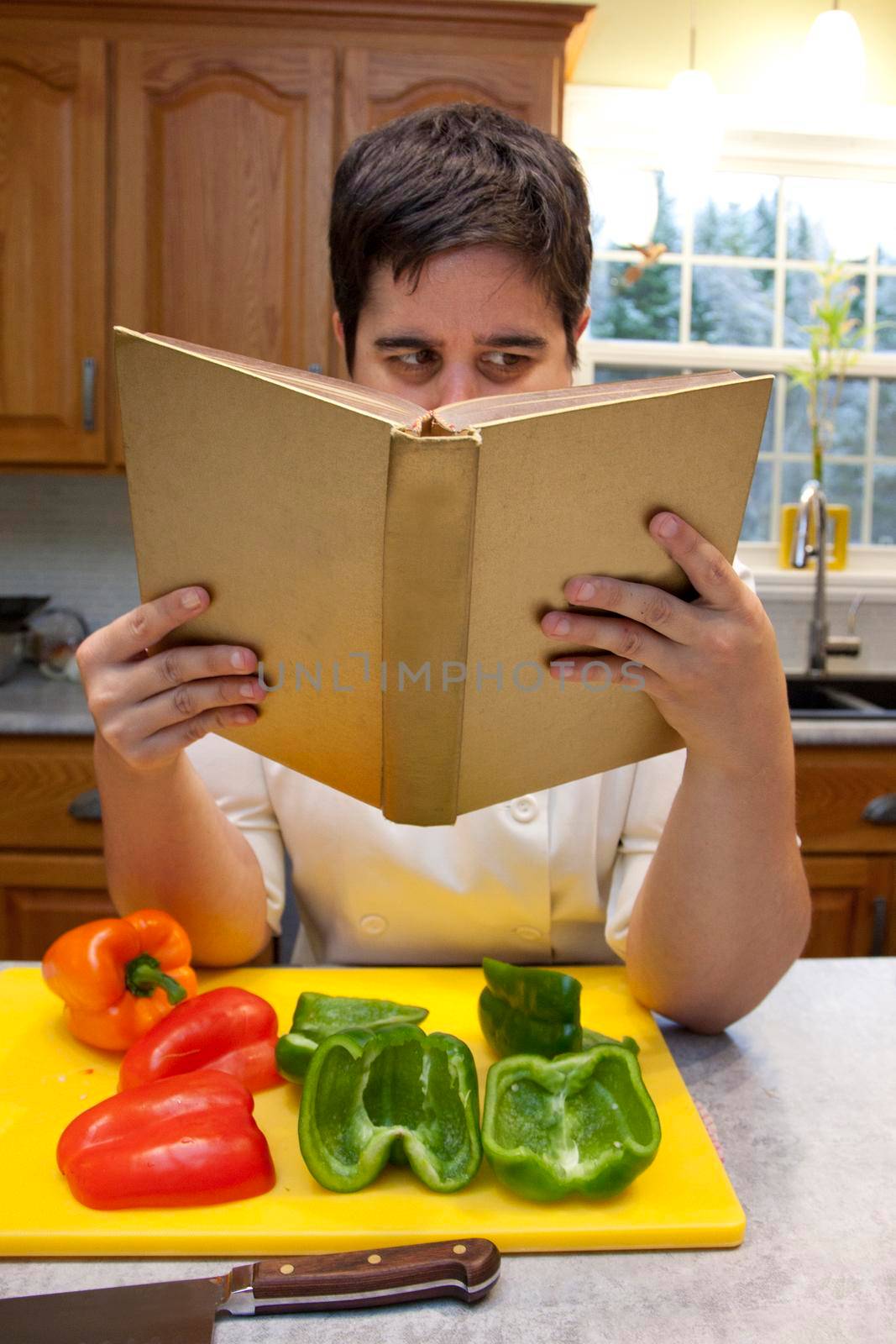 Woman peers at her cookbook in the kitchen by rustycanuck