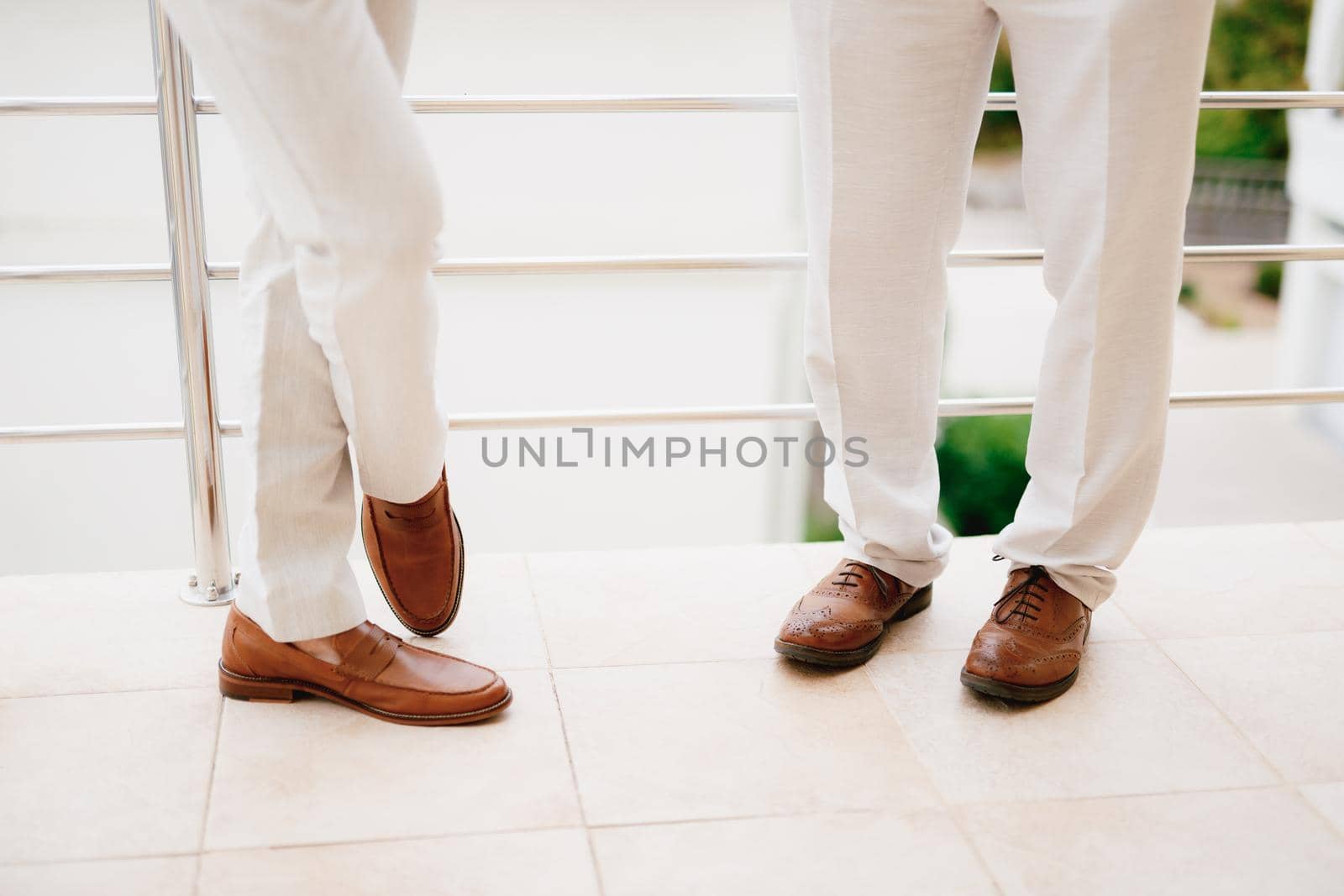 The legs of two men standing on the balcony, close-up. The groom and his best man during the preparation for the wedding ceremony. . High quality photo