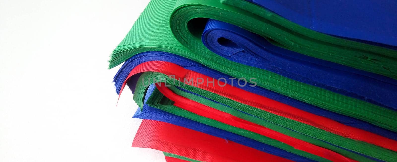 Layers of multicolored fabric in a stack on the table. Space for your text by lapushka62