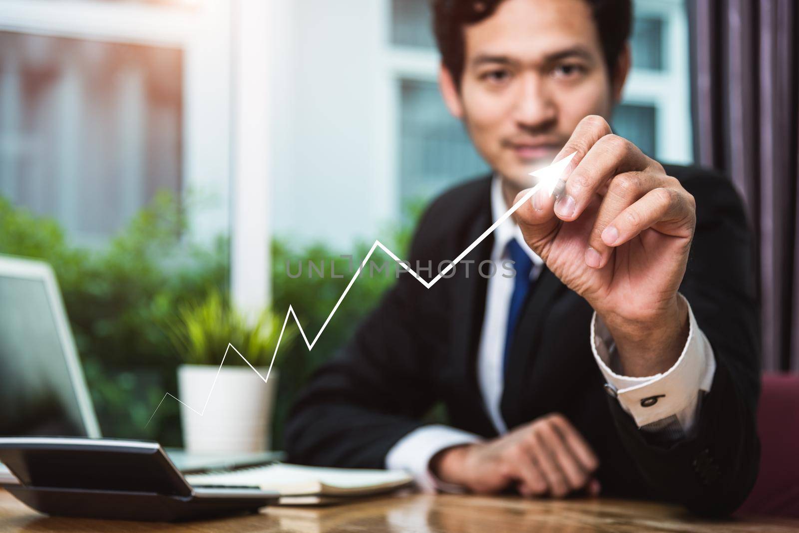 Businessman sitting at office drawing upward arrow up successful finance