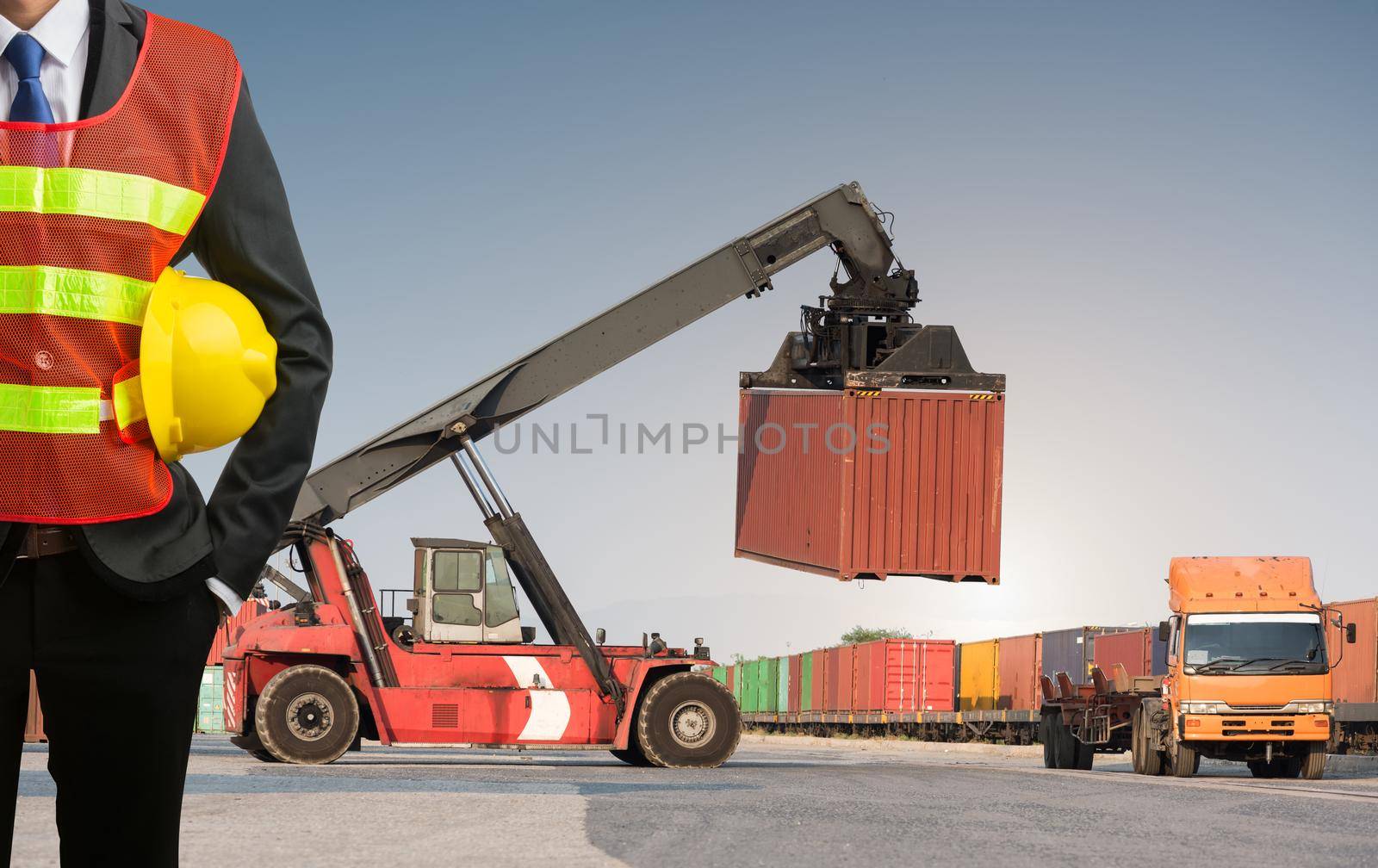 Businessman stand on front forklift loading Containers box by Sorapop
