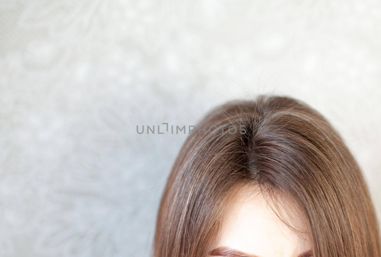 The head of a woman with a parting of gray hair. A woman does her hair. Brown hair on a woman's head close-up.