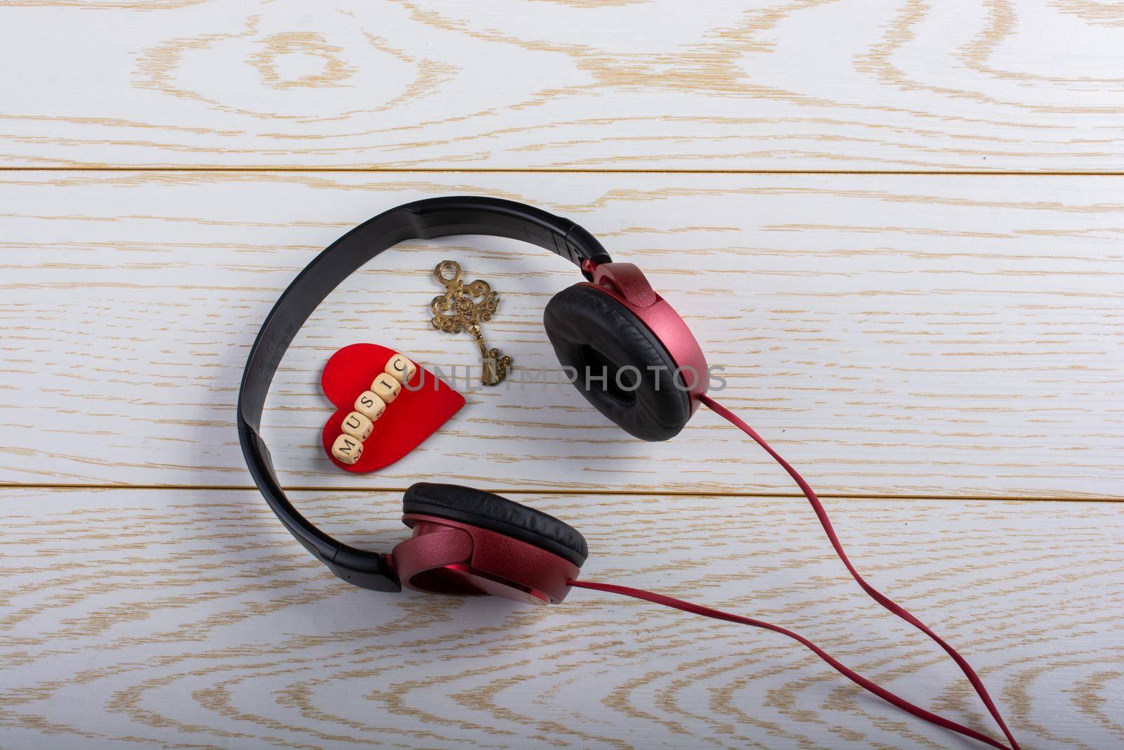 Red headphones, key and music written red heart  on a wooden background