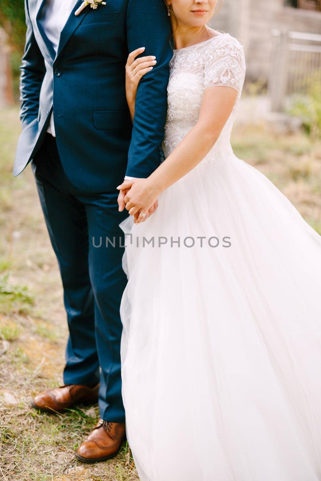 The bride and groom stand embracing, the bride holds the groom's hand and gently hugs . High quality photo