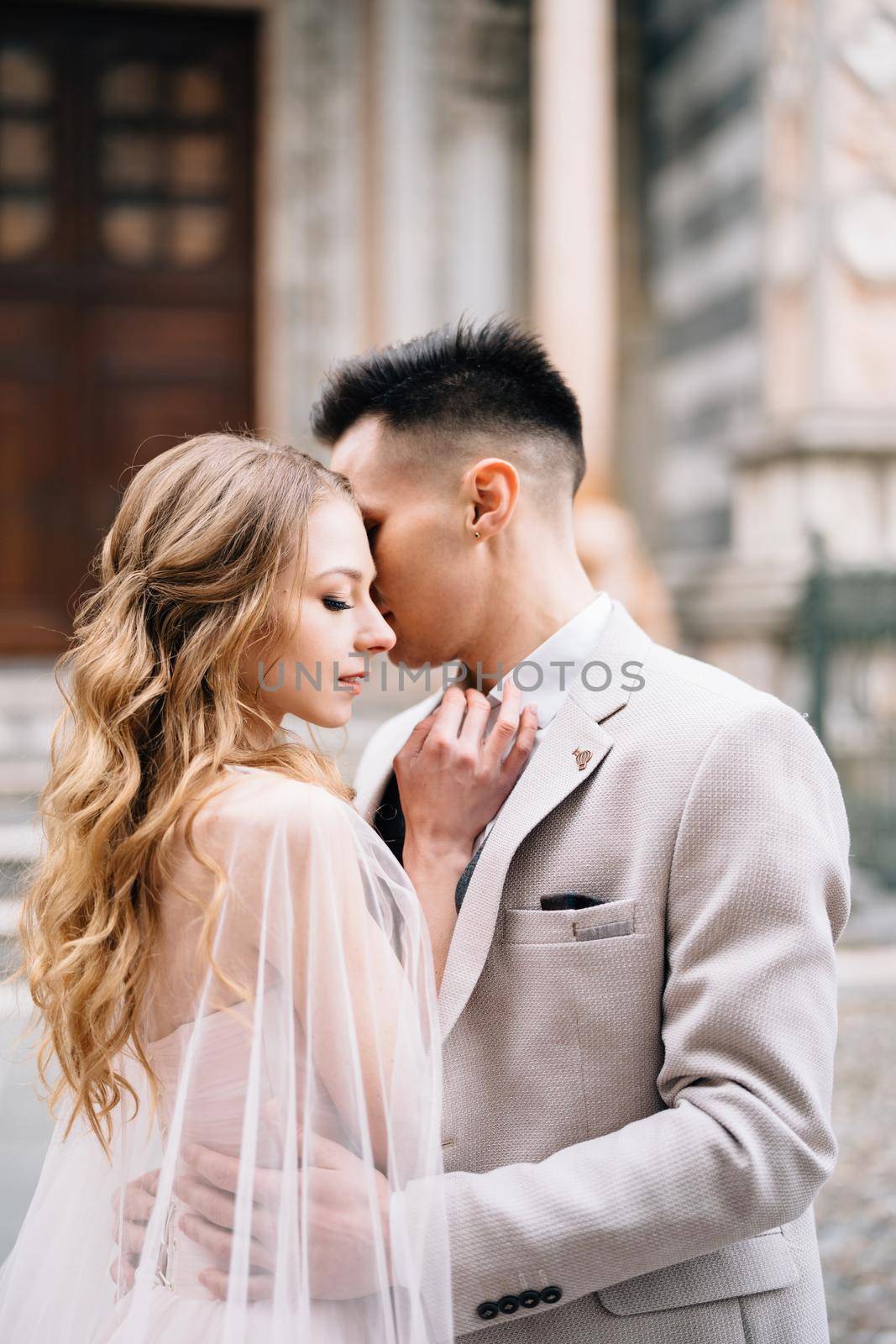 Groom hugs and kisses bride against the background of the entrance to the Basilica of Santa Maria Maggiore, Rome, Italy by Nadtochiy