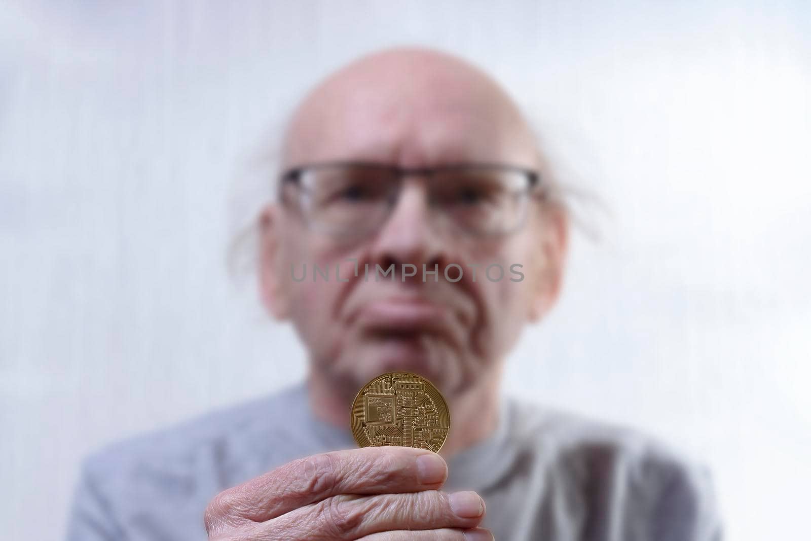 Old man holds bitcoin. A hand with a coin in focus. Head in a blur. View from the front. by Essffes