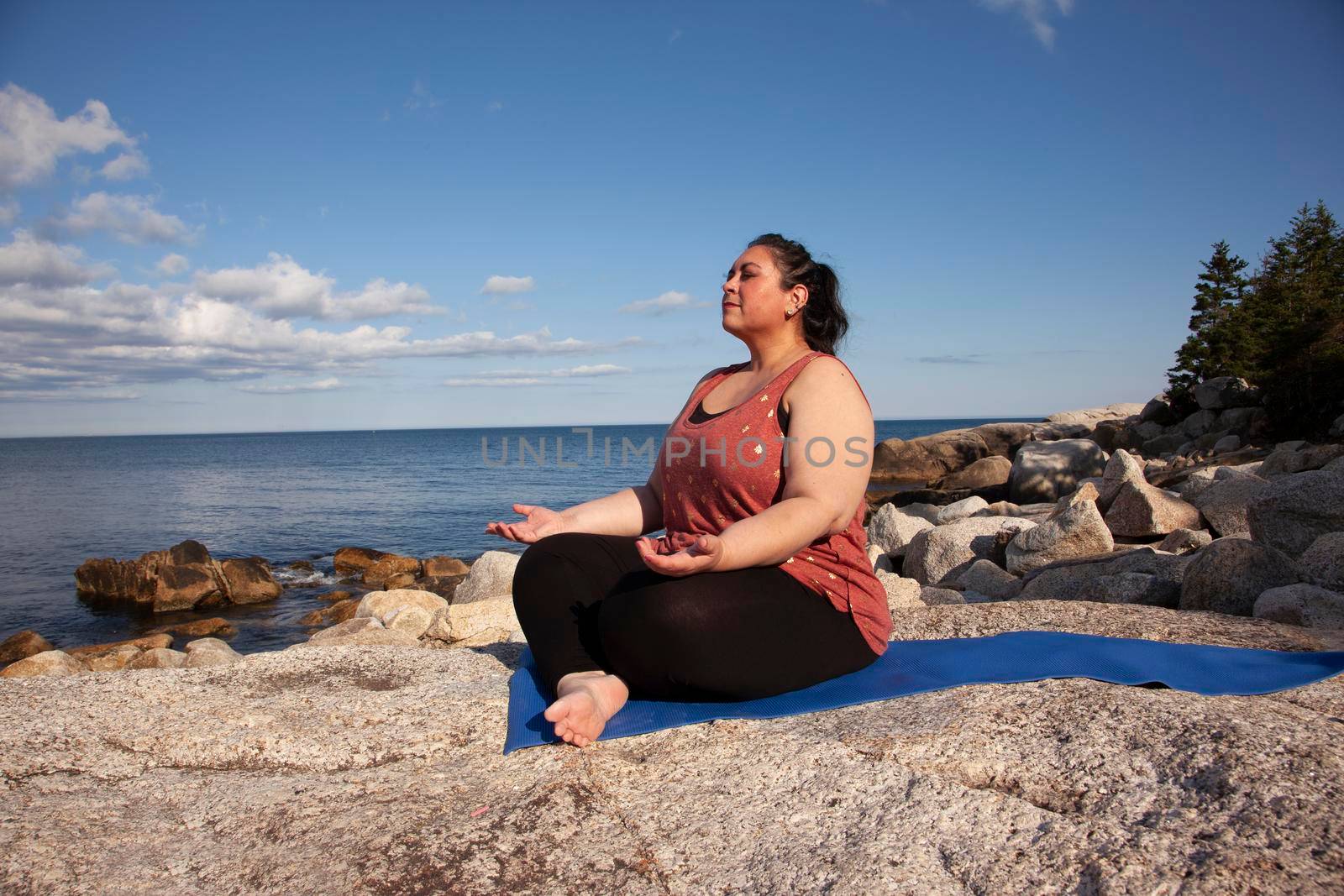 by the ocean a woman is in stillness as she meditates 