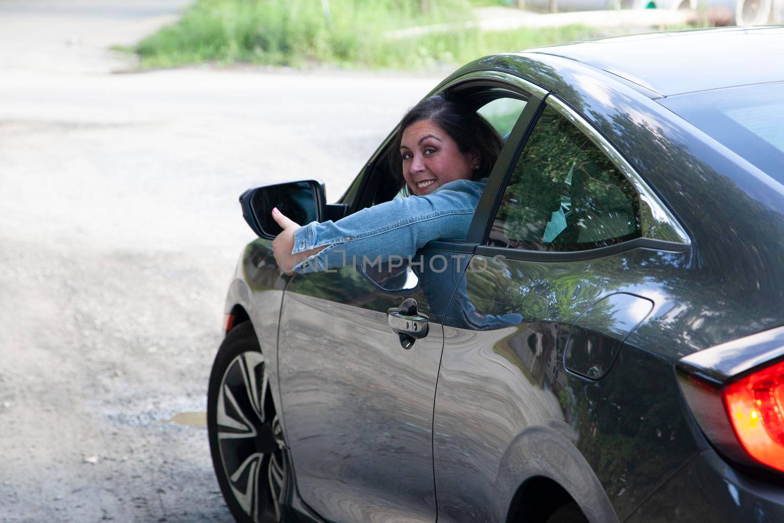 woman gives a thumbs up as she takes her car and leaves town 