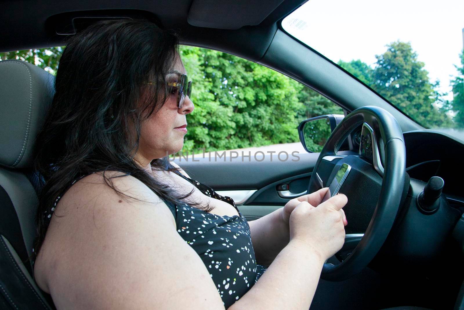 person dialling on their cell phone while inside their automobile 