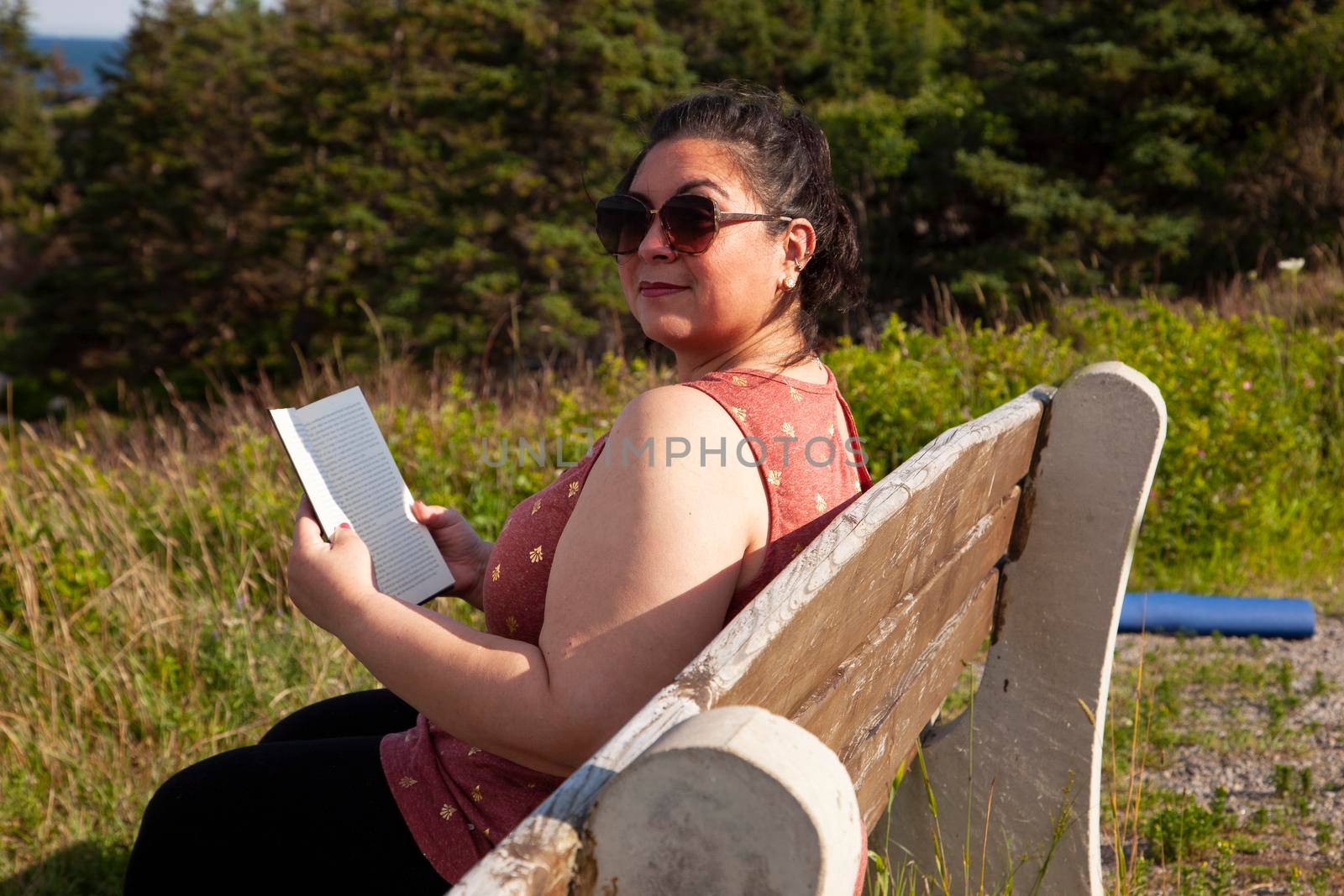 woman outside content with a book looking at the camera 