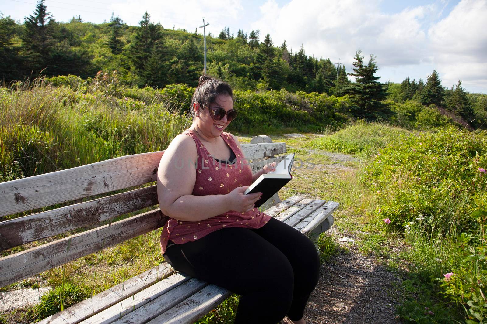 woman enjoying reading outside  by rustycanuck