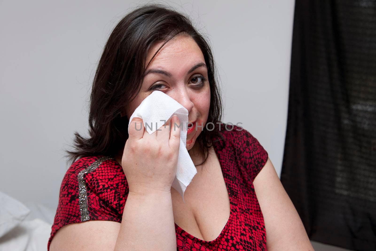 Smudged mascara and lipstick on a person's face as they wipe it clean with a tissue