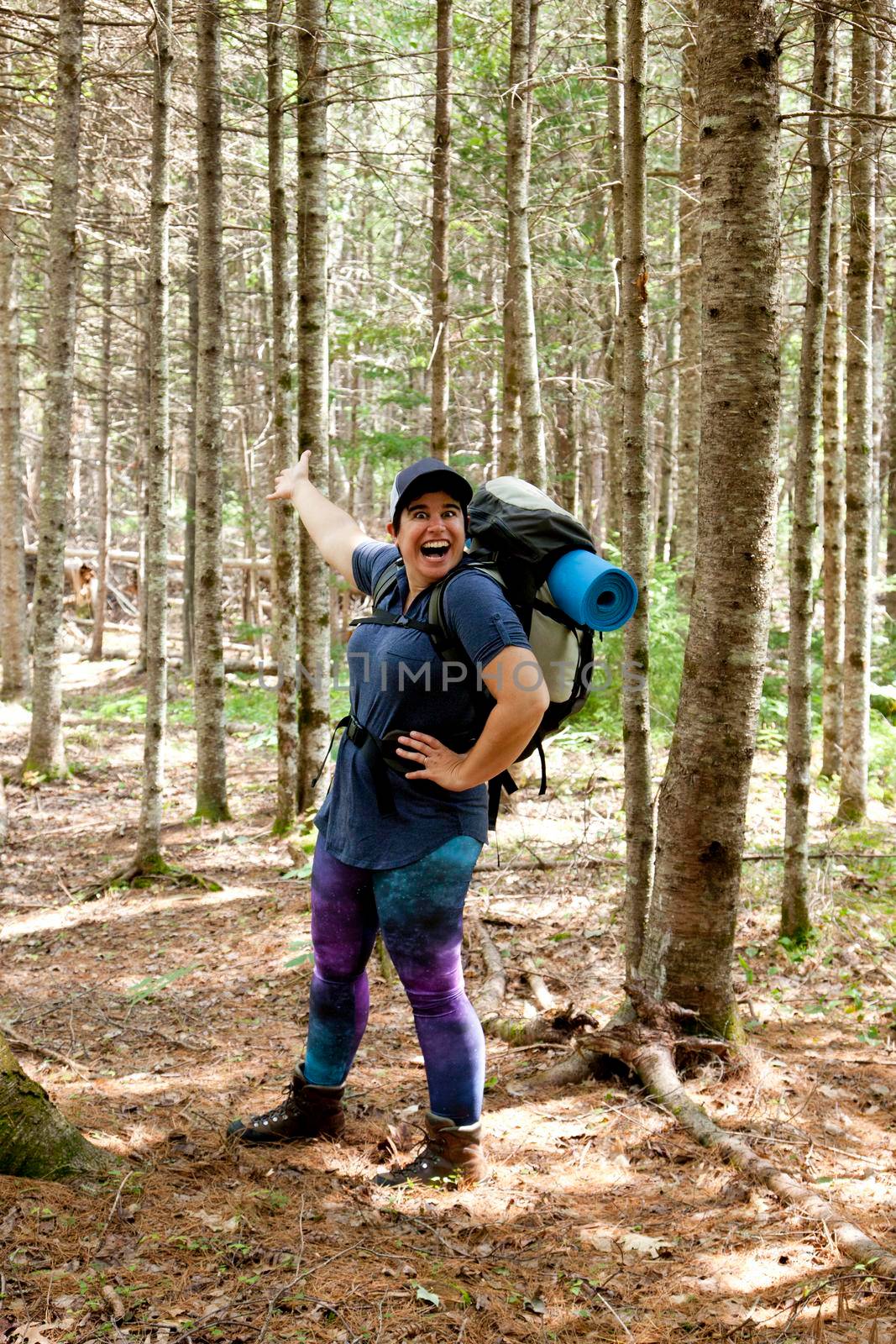 Woman hiking in the woods opens her arms, happy to show you the way through 