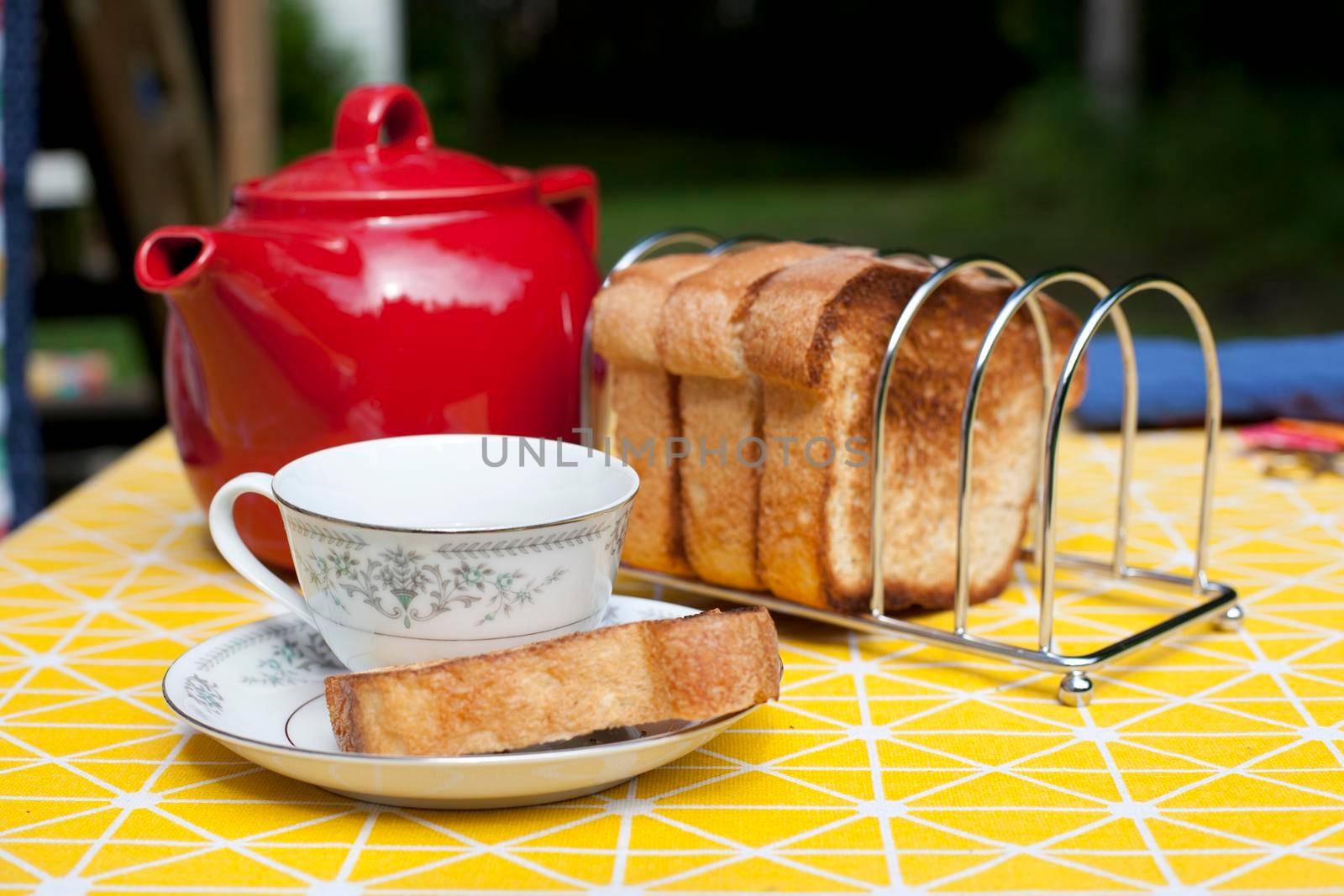 Delicious looking setup with teacup and saucer, toast, and a teapot 