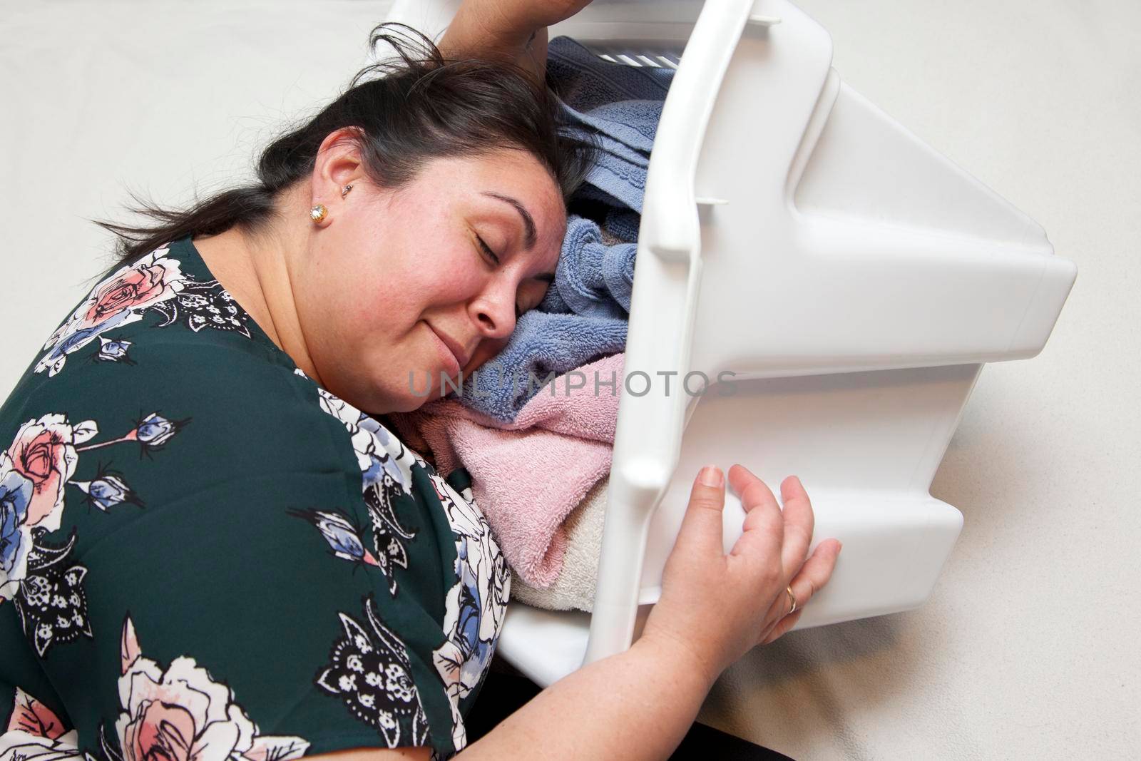 Exhausted but content woman has fallen asleep with a smile into her laundry pile