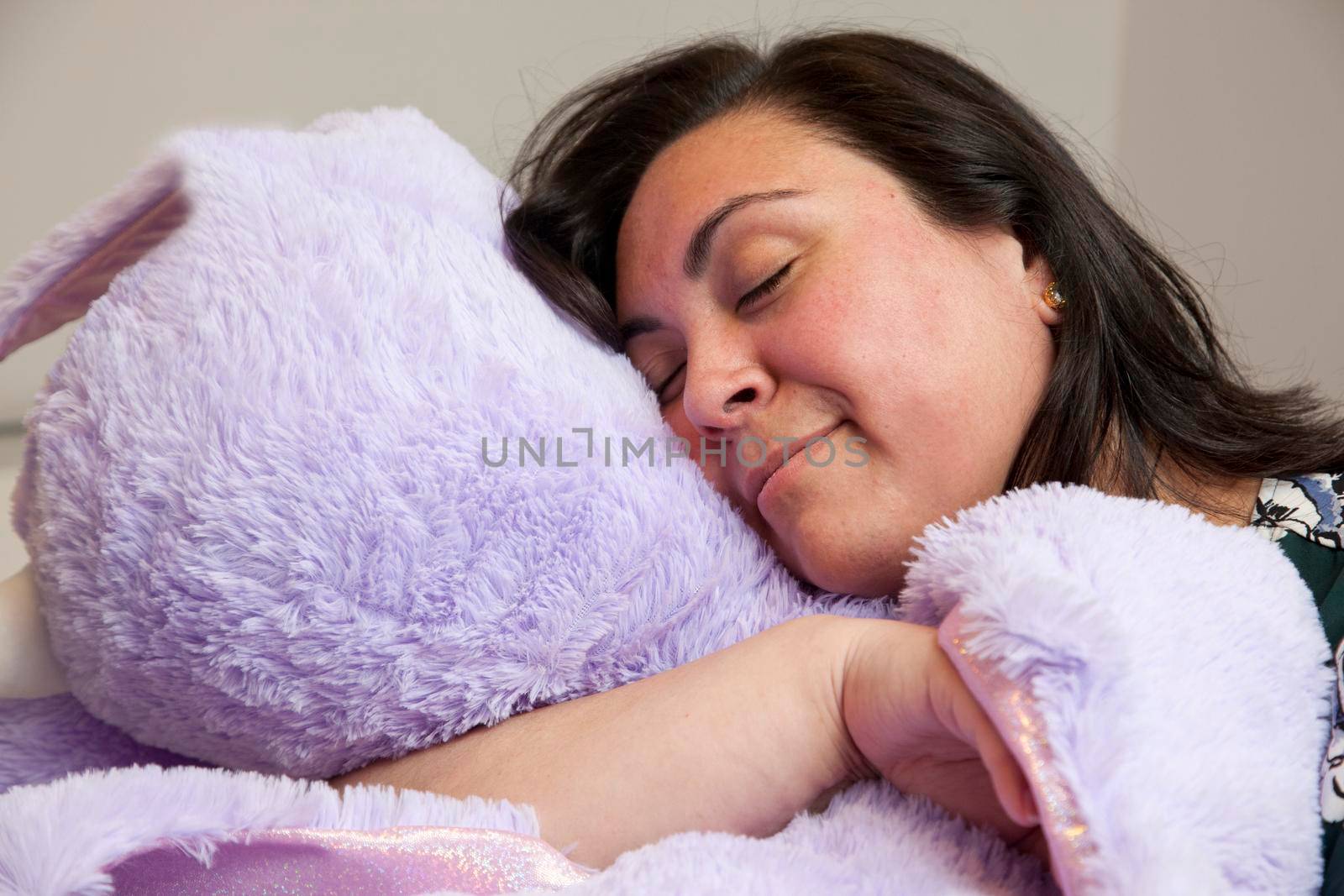 happy adult woman with her huge purple stuffed animal is asleep or resting