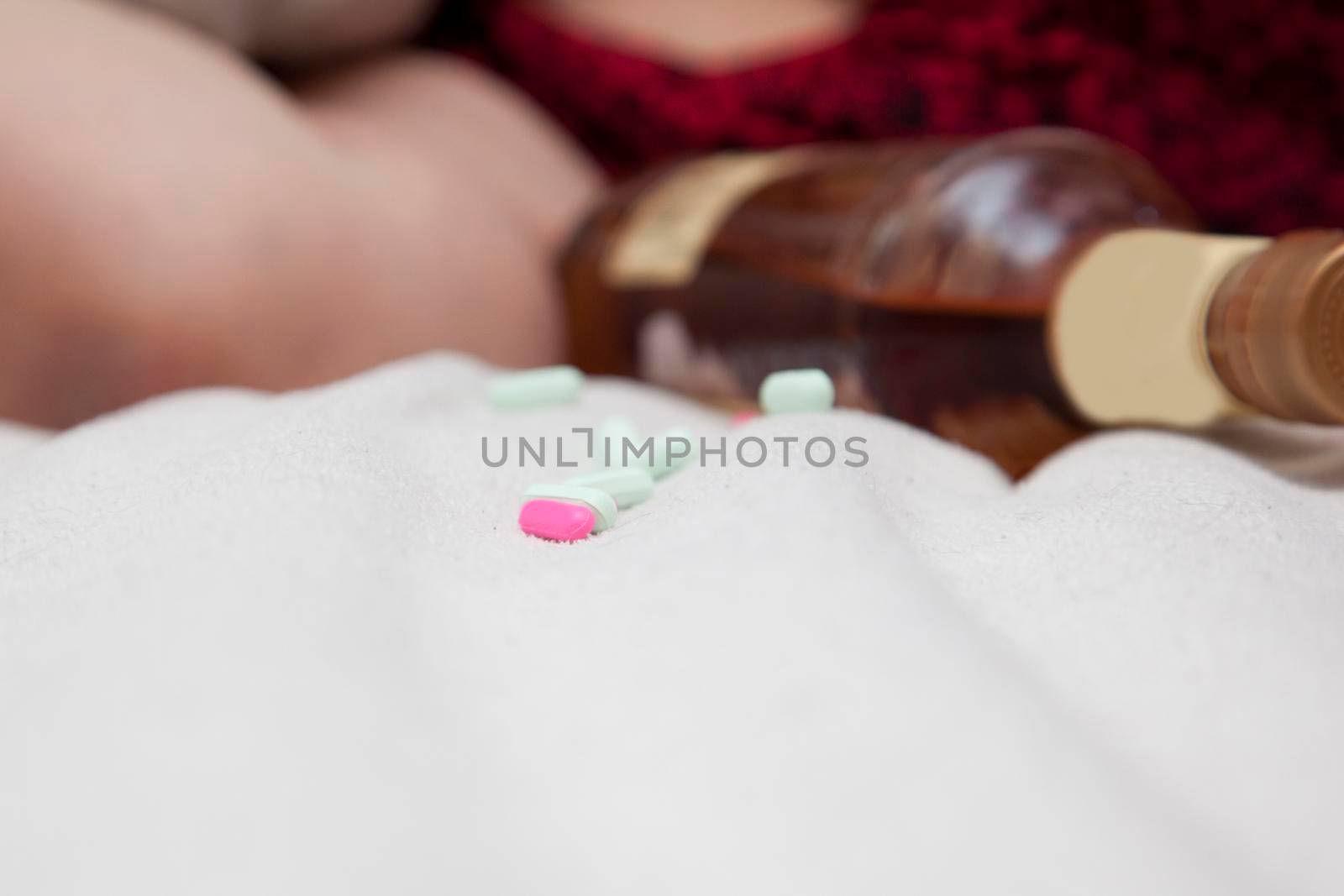 Close view on a bed with a few pills and a quart of alcohol 