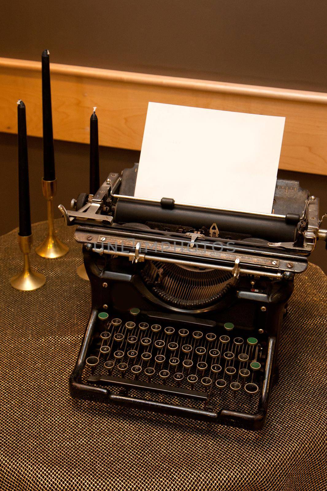 Decorative or old fashioned typewriter adding machine on a gold tablecloth with black candles 