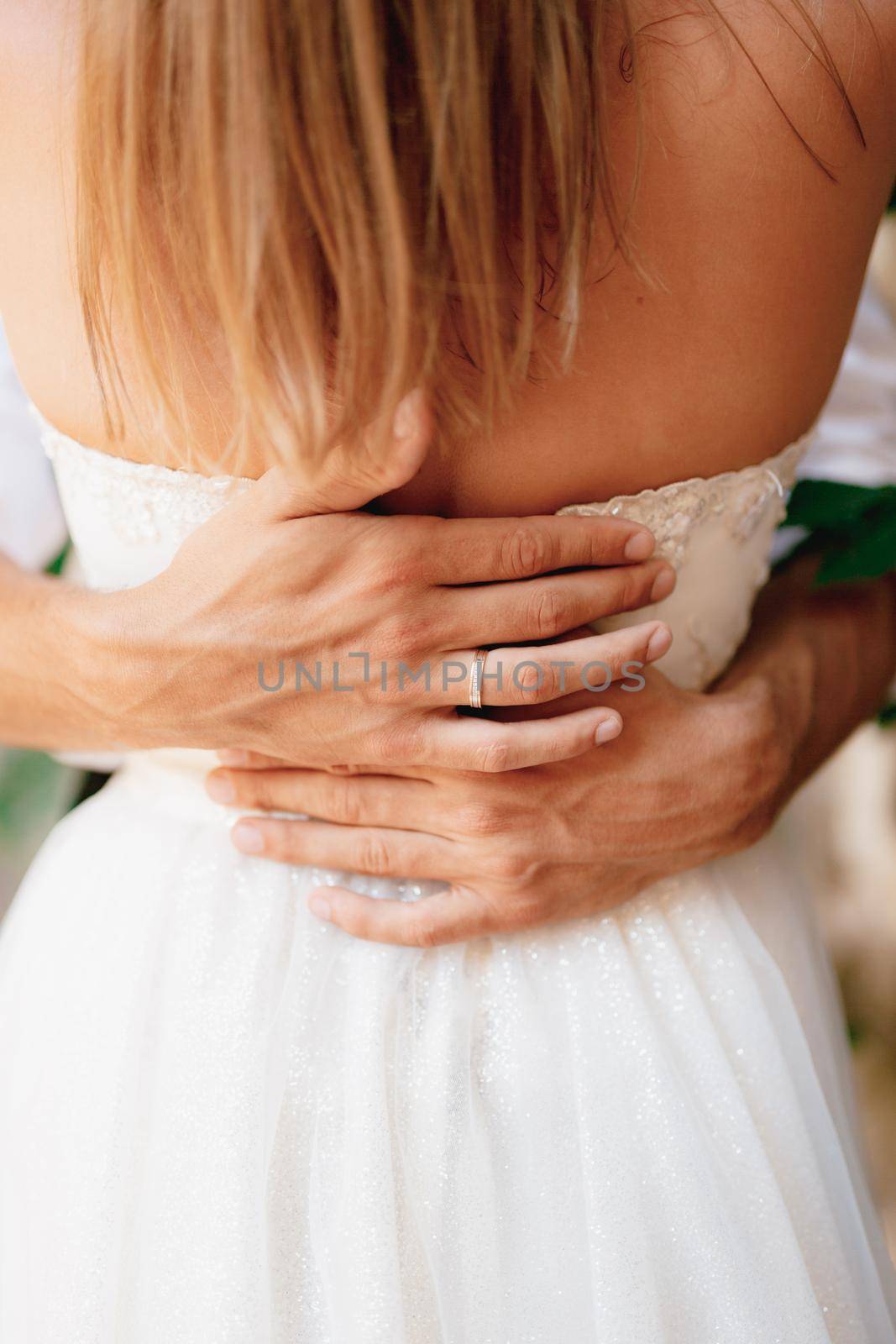 The groom gently hugs the bride and strokes her back with his hands, close-up . High quality photo