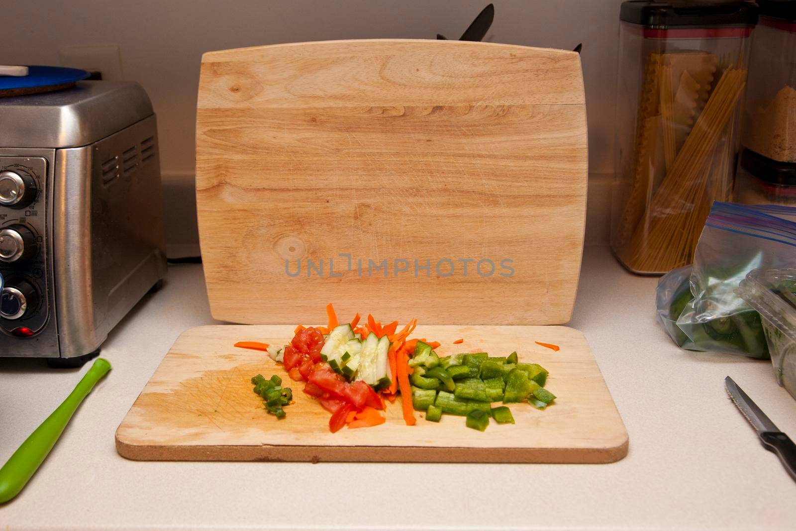  kitchen counter with area for preparing food with cutting board, knife, vegetables 