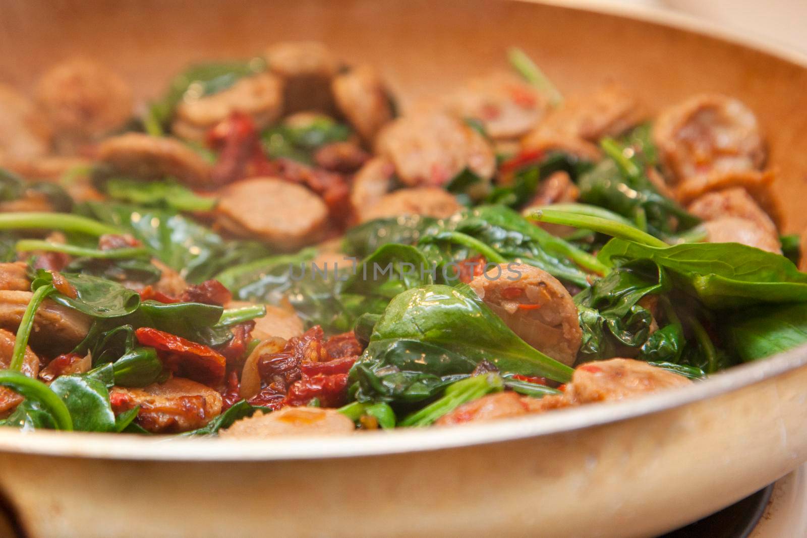  sausage, tomato and spinach meal in a skillet cooking