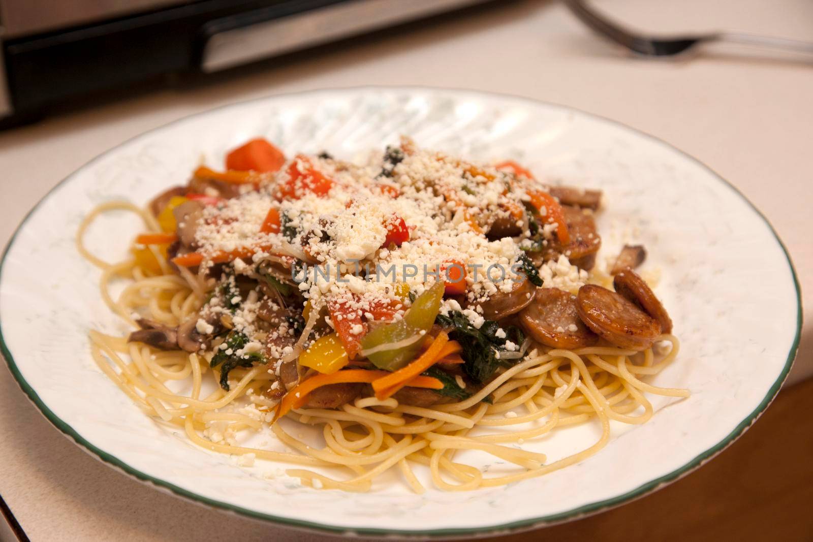  stir fry with sausage, vegetable and noodles prepared on a white kitchen plate 