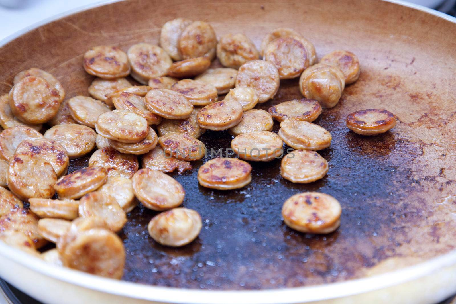  slivers of italian sausage in a skillet pan