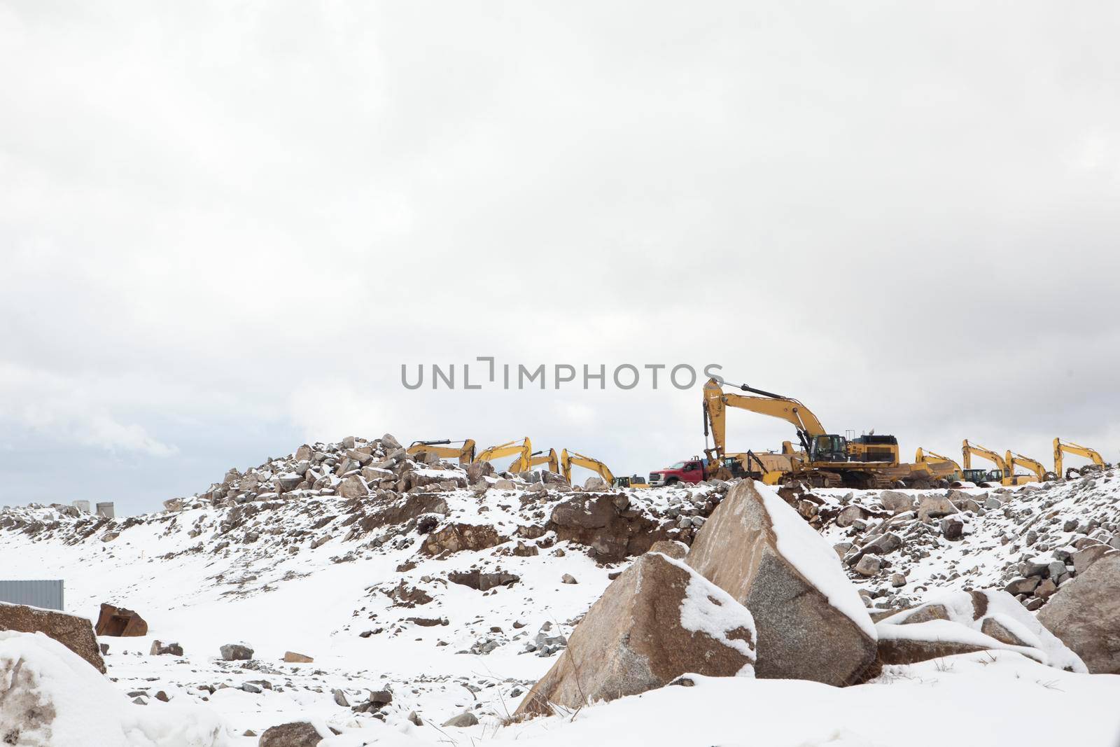  construction vehicles and backhoes at a job site in the winter snow